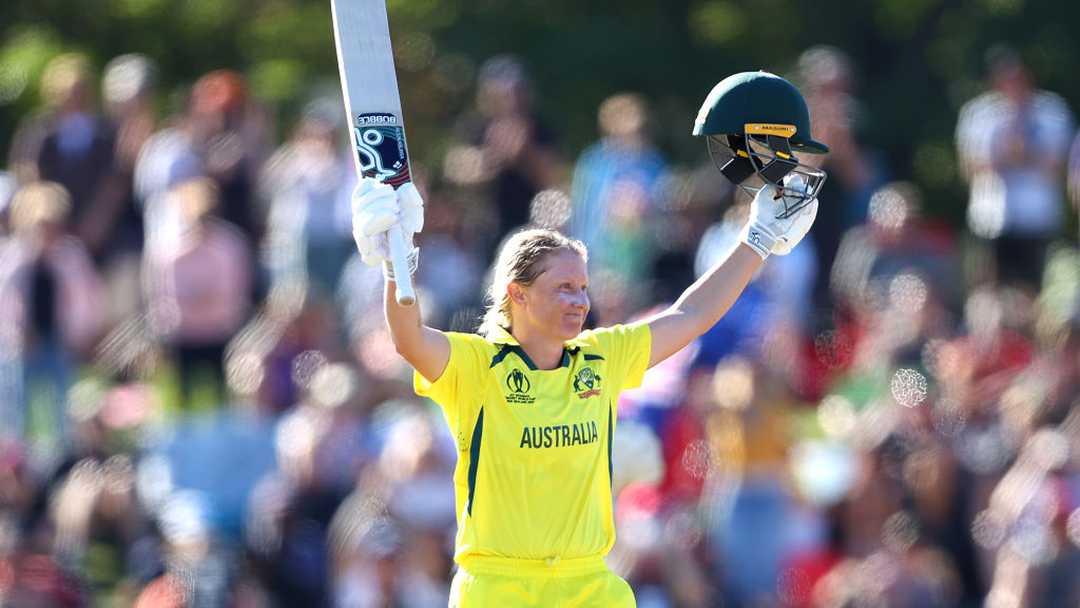 Alyssa Healy celebrating with bat and helmet raised
